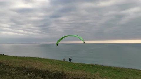 Paragliding couple preparing to fly over the cliffs edge on a cloudy day Stock Footage 150153258