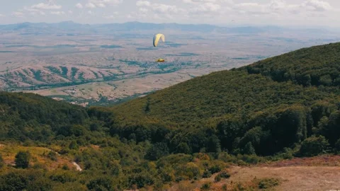 Paragliding expert gliding peacefully through the air above a forest. Fun 動画素材 269138852