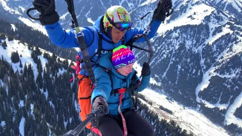 Paragliding flight with an instructor over the Karakaol mountain ski base Stock Footage 232653379