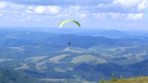 Paragliding instructor and a passenger are flying a paraglider in tandem. Stock Footage 258946185