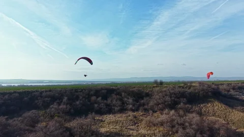 Paragliding over fields and hills in a clear sky during the afternoon in a Stock Footage 336550328