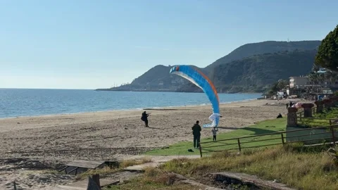 Paragliding on sandy beach with mountains in background, people enjoying ou.. Stock-Footage 336273590