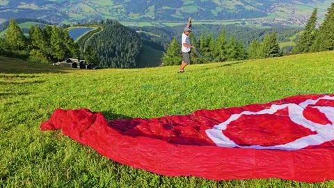 Paragliding setup in Kitzbuhel, Austria, with red parachute spread on green Video stock 337504892