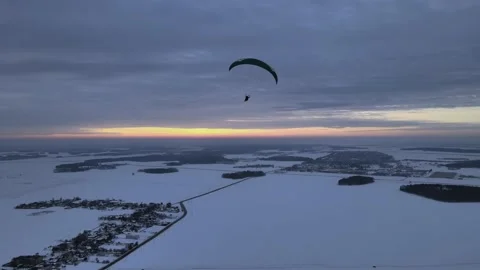 Paragliding in tandem over flat fields in winter at sunset Stock Footage 196033958
