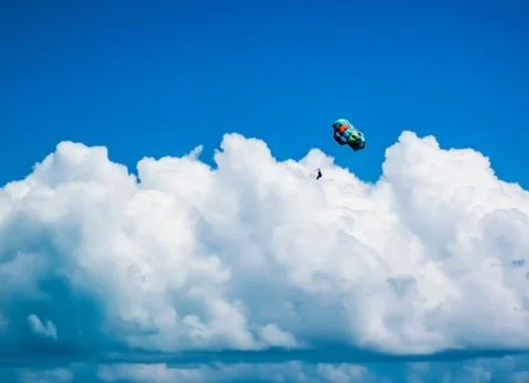 Paragliding using a parachute on the background of cloudy blue sky. Stock Photos