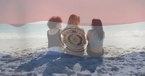 Paraguay flag animation over three women sitting on beach facing ocean Stock Footage 304408404
