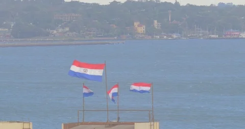 Paraguayan flags waving in the wind along banks of Paraguay river Видео 92927360
