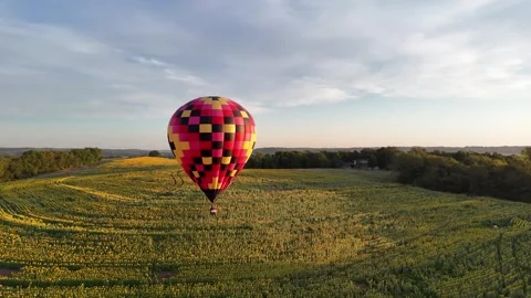 Parallax Drone Shot of a Single Checkered Hot Air Balloon Flying Low Over a Stock Footage 345536908