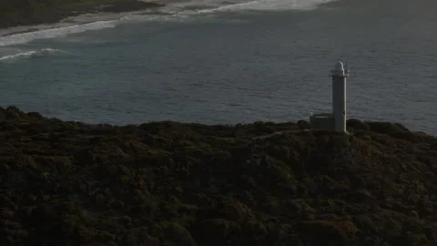 Parallax effect of the beaches behind a lighthouse as the drone circles Stock Footage 264729957