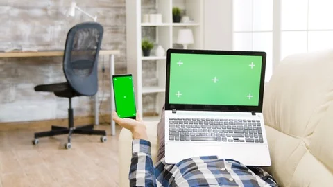 Parallax shot of man lying on the couch, holding a green screen smartphone and Stock-Footage 120021988