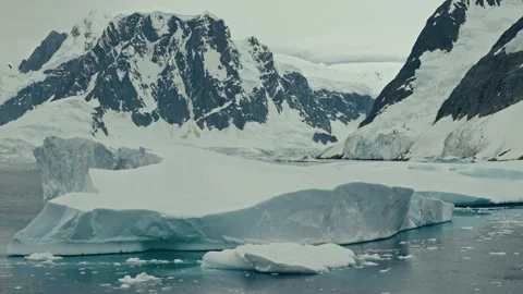 Parallax Shot Of Massive Tabular Icebergs And Snow Capped Mountains In Video stock 334093103