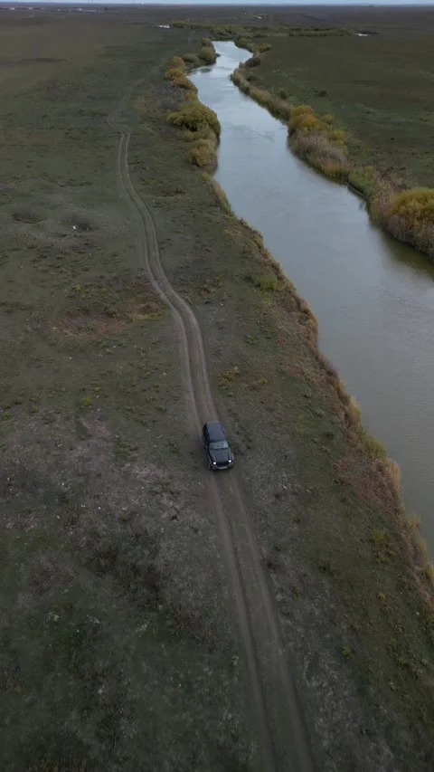 Parallel drone shot flying beside car with river on opposite side 動画素材 334330689