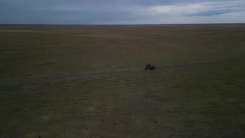 Parallel drone shot flying beside car across empty dirt road Stock Footage 334331516