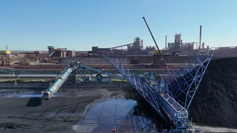 Parallel flight across coal mound and layered steel works Stock-Footage 331206128