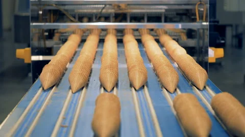 Parallel lines of waffle cones are getting pushed along the conveyor belt Stock Footage 89663179