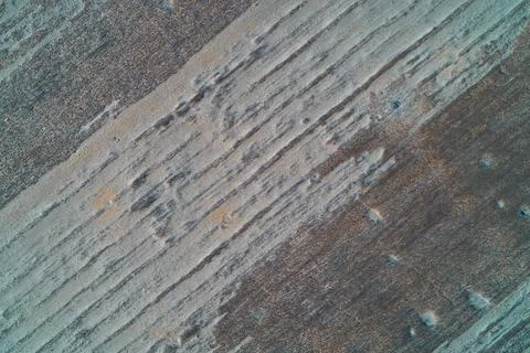Parallel plowed furrows texture in frozen agricultural field with blue frost Stock Photos