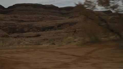 Parallel tracking shot of UTV in red sand desert in Utah under sandstone cliffs Stock Footage 234033538