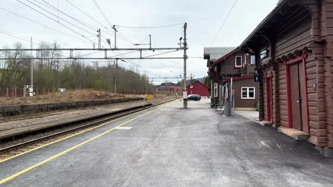 Parallel tracks sit under electric lines traditional wooden station buildings Stock Footage 326361818