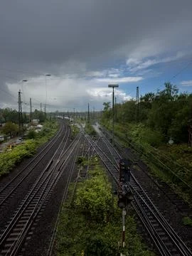Parallel train tracks with overhead wires surrounded by lush greenery Stockfoto's