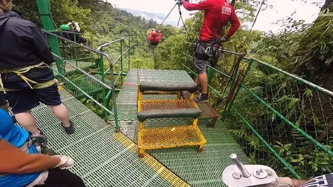On parallel ziplines, two riders take off simultaneously, quickly Video stock 114343990