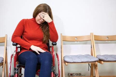 Paralyzed legs Disabled sad woman in invalid chair covers her face with hand  Foto stock