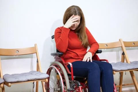 Paralyzed legs sad woman in invalid chair covers her face with hand while sit 스톡 사진