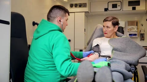 A paramedic carefully examining a patient inside an ambulance, professional care Stock Footage 305538248