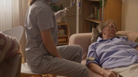 Paramedic Checking and Controlling Drip while Senior Woman Taking Nap Stock Footage 335882232
