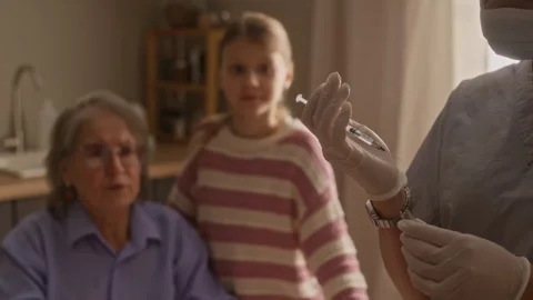 Paramedic Drawing Up Syringe while Granny and Granddaughter Communicating Stock Footage 335882570