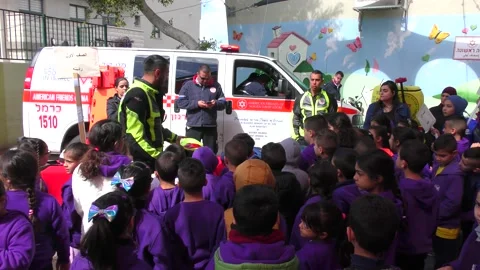 A paramedic explaining school children about emergency services during drill Видео 135359476
