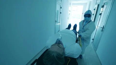 Paramedic in a hazmat suit is relocating a lying patient 스톡 동영상 130879035