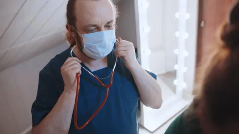 Paramedic home consultation checking vitals equipment and notes wearing mask 動画素材 342337442