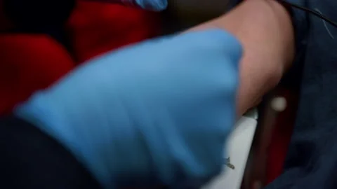 Paramedic inserting needle cannula in arm. Worker placing IV catheter into vein Stock Footage 166865234