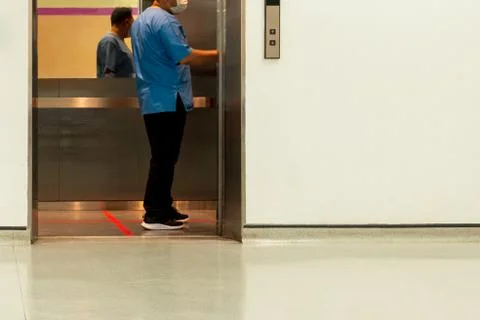 Paramedic inside elevator with red line standing position prevention COVID-19. Stock Photos