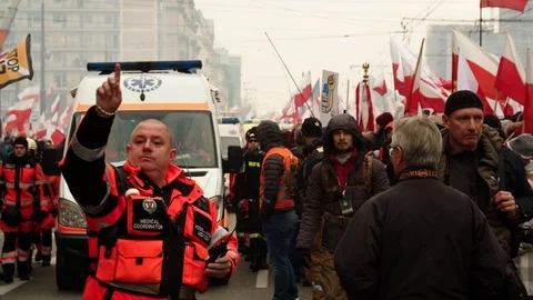 Paramedic moving crowd away opening way for road for row of ambulances in 動画素材 121999540