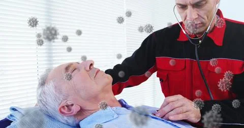 Paramedic in red uniform pressing stethoscope against elderly patient on bed in Stock Photos