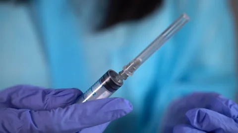 The paramedic removes the cap from the needle. Slow motion Vídeo Stock 128842489