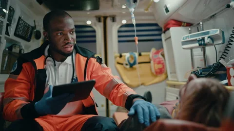 Paramedic Riding in Ambulance Using Tablet with Patient Stock-Footage 141570108