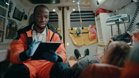 Paramedic Riding in Ambulance Using Tablet with Patient Stock-Footage 141570109