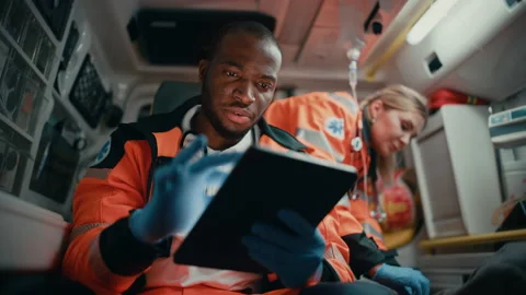 Paramedic Riding in Ambulance Using Tablet with Patient Stock Footage 141570260