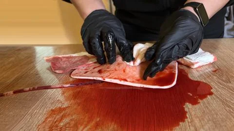 Paramedic training: on a table with artificial blood, female hands in black Stock Photos