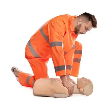 Paramedic in uniform practicing first aid on mannequin against white backgrou Stock Photos