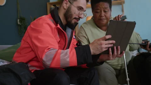 Paramedic Using Digital Tablet while Communicating with Senior Woman Stock Footage 318894551