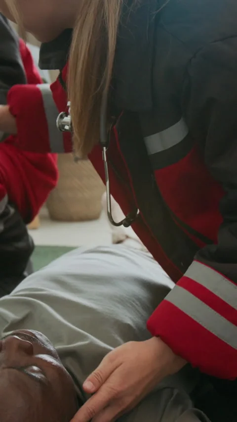 Paramedic Using Penlight to Examine Unconscious Man Lying on Floor Stock Footage 294737057