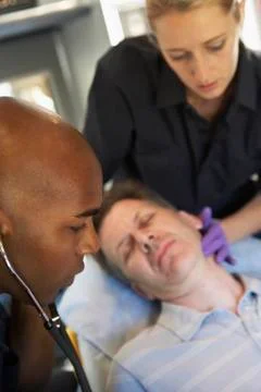 Paramedic using stethoscope on patient in ambulance Foto stock
