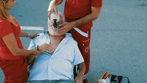 Paramedic workers is putting an oxygen mask on a senior male patient Stock Footage 211819621