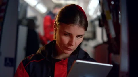 Paramedic working on tablet computer. Pensive woman surfing social media network Stock Footage 166865177