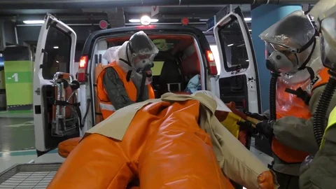Paramedics dressing protective suit unload injured manikins Stockbeeldmateriaal 81419567