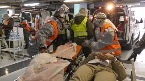Paramedics dressing protective suits unload injured manikins from ambulance 스톡 동영상 81425658