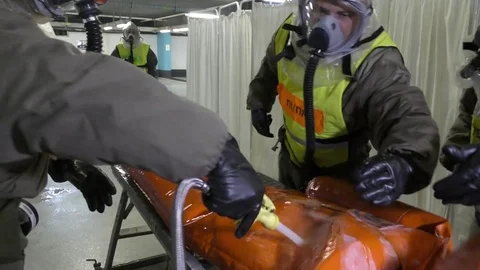 Paramedics dressing protective suits wash chemical attack victim Stock Footage 81443313